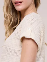 Blusa celeste de tejido calado tipo pointelle, con escote redondo, mangas cortas con dobladillo y presilla con botón, y ruedo curvo.