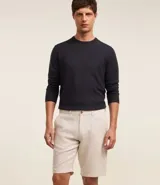 Bermuda de hombre en lino color gris claro, de corte recto, con textura discreta, bolsillos laterales y cierre frontal con botón y cremallera.