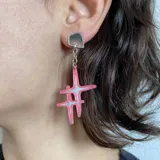 Aros colgantes con base plateada y dije de dos estrellas superpuestas de acrílico rosa con detalles en blanco.