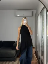 Musculosa de cuello alto con diseño irregular y bajo asimétrico, confeccionada en tela tipo cey con detalle de puntilla en el ruedo.