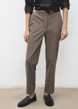 Pantalón de tiro medio color marrón con sutil diseño de raya diplomática, de corte entallado y diseño crop. Cuenta con bolsillos laterales, trabillas y cierre frontal con cremallera, botón y ganchos ocultos.