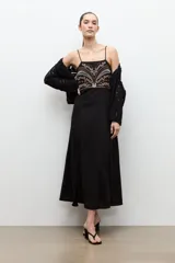 Maxi vestido largo de color negro, de corte recto y tirantes finos. Presenta un diseño bordado multicolor en la zona del pecho con motivos geométricos y florales.