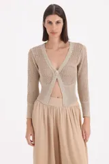 Saco corto de tejido de punto con acabado en lurex, de manga larga y escote en V con cierre de un solo botón frontal. Presenta una textura calada en las mangas y el cuerpo.