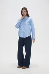Camisa de algodón blanca, de corte entallado al cuerpo, con cuello camisero, manga larga y cierre frontal de botones.