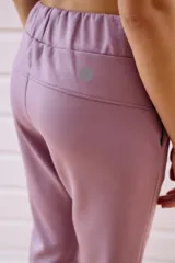 Pantalón babucha deportivo color lila, con elástico en la cintura y puños, cordones regulables y dos bolsillos laterales.