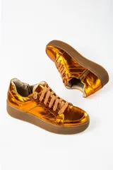 Zapatillas deportivas color naranja metalizado con cordones marrones y suela marrón.