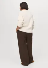 Pantalón de vestir marrón de tiro bajo y diseño wide leg, con pinzas frontales, trabillas para cinturón, bolsillos laterales y cierre oculto con botón, gancho y cremallera.