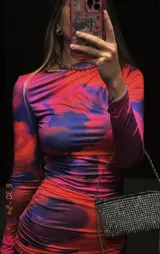 Vestido midi ajustado con estampado abstracto en tonos naranja, rosa y azul. Tiene cuello alto y mangas largas.