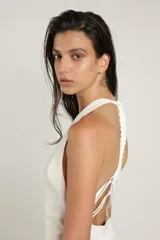 Chaleco largo color blanco de mezcla de viscosa con cuello halter, espalda descubierta, cierre con botones en la parte delantera y detalle de trenza.