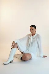 Blusa plisada de corte amplio y fluido, color bordó, con cuello alto y lazo decorativo. Presenta mangas largas con volumen y puños ajustados.