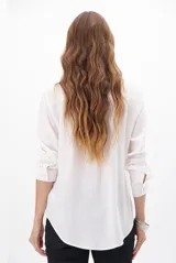 Camisa blanca de manga larga con cuello clásico, cierre de botones frontal y bolsillo de parche en el pecho.