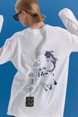 Remerón de manga larga y corte holgado, color blanco, con estampa serigráfica en la espalda que incluye motivos orientales como una rama de flores, un pez koi, una mariposa y texto en japonés. Presenta un parche decorativo en la parte inferior.