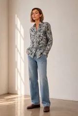 Camisa de manga larga con cuello clásico y cierre frontal de botones, con estampado botánico de hojas en tonos azules y blancos.