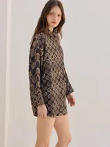 Camisa de algodón con estampado geométrico de ondas en tonos marrón y negro, corte holgado, mangas largas y cuello clásico.