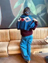 Canguro tejido en lana merino color azul con apliques geométricos en terciopelo bordados a mano.