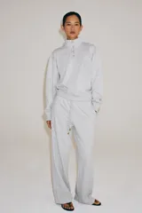 Pantalón ancho de felpa en color gris melange, con tiro medio y cintura elástica ajustable con cordón. Cuenta con bolsillos laterales ocultos en costura y diseño de pernera ancha.