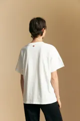 Remera de manga corta color marrón, con cuello redondo y cierre frontal parcial con botones. Presenta un diseño de calce relajado y líneas simples.