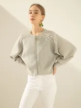 Campera bomber gris confeccionada en tejido combinado de neoprene, con escote bordado artesanalmente con piedras y cierre frontal con cremallera.