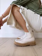 Botas Chelsea de cuero color crudo con elástico lateral, suela track color caramelo y tirador trasero de cuero con textura croco color marrón.