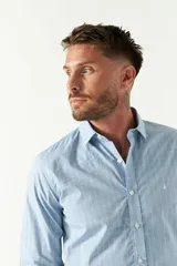 Camisa de manga larga para hombre, color azul claro con microestampado de cuadros. Presenta un corte slim y cuello abotonado.