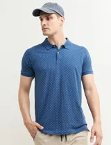 Remera polo azul con estampado de pequeños puntos blancos, cuello y puños acanalados, y cierre de dos botones.