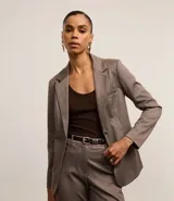 Blazer slim de punto roma color marrón con cuello solapa, abotonado delantero de botón doble forrado, bolsillos tipo cuchillo y manga larga.