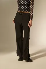 Pantalon de vestir negro de corte flare, con cintura alta y detalle de tachas metálicas en el ruedo.