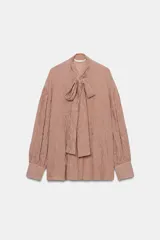 Camisa de algodón con estampado de rayas verticales, cuello subido con lazada frontal, manga larga abullonada y puños ajustados.
