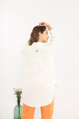 Camisa blanca amplia de manga larga con ruedo curvo.