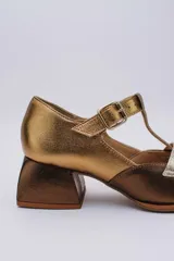 Zapato Mary Jane de cuero color bronce y dorado, con puntera redondeada, tira sobre el empeine con hebilla y tacón cuadrado.