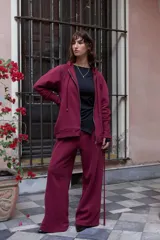 Campera deportiva oversize color bordó con capucha, cierre metálico frontal y mangas raglán de volumen pronunciado. Cuenta con puños largos de rib elástico y cordones regulables a tono con terminaciones metálicas.