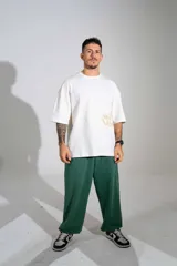 Remera oversize de algodón color off-white, con mangas cortas amplias y cuello redondo. Presenta un pequeño estampado en el centro del pecho y un diseño gráfico más grande en el lateral inferior.