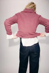 Jersey de punto confeccionado en hilatura con lana, con diseño de rayas horizontales en tonos rojo y gris. Presenta cuello solapa, escote en V y detalle de botones decorativos en el cuello y la solapa.