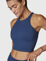 Top deportivo color azul denim, de sujeción media y diseño crop top, con espalda cruzada y tecnología Aloe Vera.