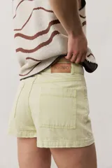 Short gris claro de tiro alto con costuras pespunteadas en contraste y bolsillos traseros amplios. Presenta una etiqueta de cuero rojo en la parte posterior de la cintura.