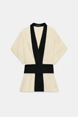 Kimono Zara Woman Collection de manga corta y cuello en V, confeccionado en tejido color crudo con sutiles rayas verticales. Presenta aplicaciones de terciopelo negro a contraste en la solapa y un fajín ancho integrado en la cintura.