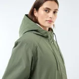 Parka larga de color verde con capucha ajustable mediante cordones y forro interior de efecto borreguito. Presenta un cierre frontal de cremallera oculto por una solapa con botones a presión y dos bolsillos grandes de parche con solapa en el frente.