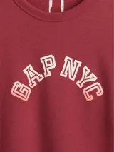 Buzo deportivo Gap color crudo, de corte recto, con cuello redondo y logo Gap NYC estampado en verde.