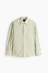 Camisa de popelina de algodón con cuello inglés, tapeta clásica, bolsillo superior abierto y canesú con pliegue en la espalda. Cuenta con mangas largas, puños ajustables con botón y bajo ligeramente redondeado. Presenta un diseño de rayas verticales en tonos verde y blanco.