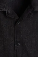 Camisa de denim negro, corte regular fit, con cuello resort, manga corta, tapeta lisa y bajo recto.