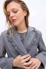 Blazer gris a rayas con solapa de volados, manga larga y lazo ajustable en la cintura.