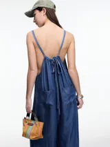 Enterito de denim suave confeccionado en 100% lyocell, con escote recto y breteles finos regulables que se ajustan en la espalda. Presenta una silueta amplia de pierna recta, caída fluida, bolsillos traseros aplicados y costuras a contratono.