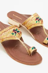 Sandalia de tacón bajo marca Rapsodia, con diseño de dedo y tira ancha sobre el empeine. Presenta bordados coloridos y lentejuelas doradas sobre una base textil dorada. Cuenta con un taco bloque de 3 cm y suela de caucho con grabado decorativo.