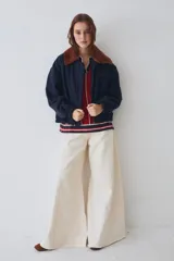 Campera bomber de paño color azul marino, con cuello de piel sintética en color marrón desmontable, cierre frontal y puños elásticos. Presenta logo bordado en el frente y bolsillos laterales.