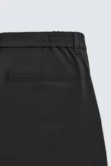 Pantalón de corte regular fit, color negro, confeccionado en tejido elástico. Presenta cintura elástica, cierre frontal con cremallera y botón, bolsillos laterales y bolsillos traseros de vivo.