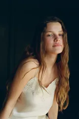 Top lencero color beige claro, confeccionado en mezcla de seda, con escote en pico y tirantes finos. Presenta una aplicación de encaje a tono en el escote.