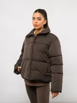 Campera puffer corta Umbro de color negro, con cuello alto, cierre frontal y bolsillos laterales. Presenta un diseño acolchado y logo de la marca bordado en el pecho.