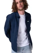 Camisa de manga larga de popelina color azul marino, de corte clásico con cuello camisero, cierre frontal con botones y bolsillo en el pecho con etiqueta de la marca Caterpillar. Incluye sistema para convertir las mangas en cortas.