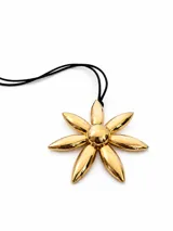 Collar con dije de flor grande en color dorado brillante, montado sobre un cordón negro fino.