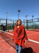 Capa color naranja de lana merino con cuello redondo y diseño con pespuntes en la espalda.